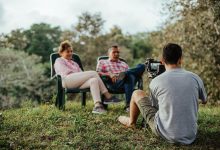 Casal de turistas sendo entrevistado ao ar livre em um jardim.