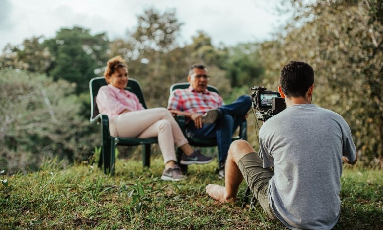 Casal de turistas sendo entrevistado ao ar livre em um jardim.