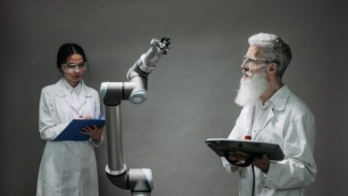 Dois pesquisadores trabalham com um braço robótico em um laboratório.