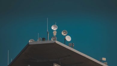 Antenas parabólicas e equipamentos de comunicação vistos de baixo contra um céu azul.