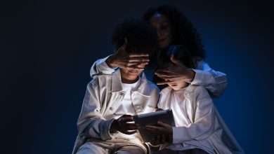 Mãe acompanha duas crianças enquanto elas usam um tablet em casa.
