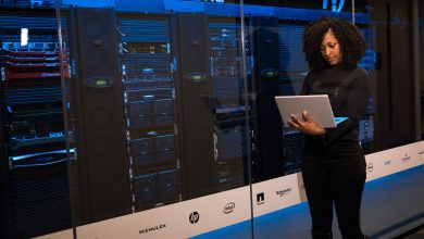 Profissional usando um laptop enquanto monitora servidores em uma moderna sala de datacenter